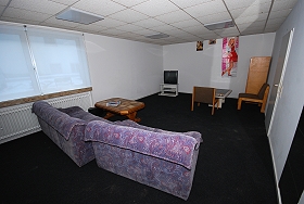 Das Bild zeigt Sessel, Tische und den Fernseher im Fernsehraum.